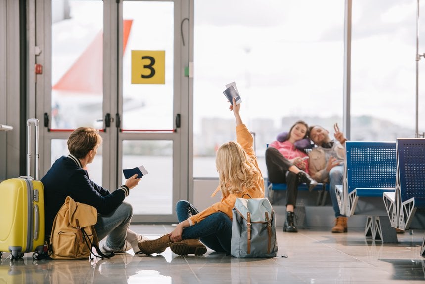 Travellers with luggage waiting at an airport gate.